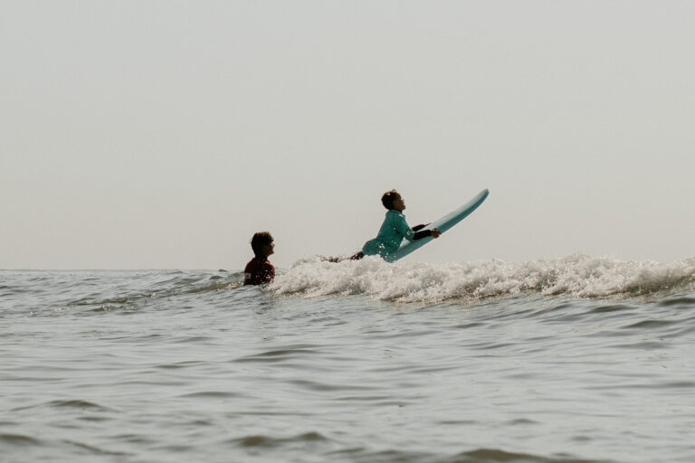 Im Kindersurfkurs auf Sylt lässt Surflehrer Kind über Welle fliegen